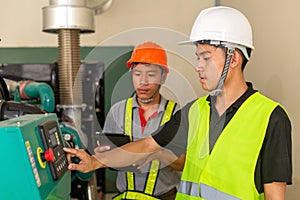 Two asian maintenance technician checking technical data of water pressure control system equipment in factory