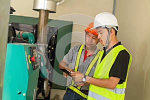 Two asian maintenance technician checking technical data of water pressure control system equipment in factory