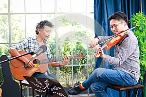 Two asian men playing the violin classical instrumental and acoustic guitar