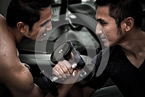 Two Asian men use dumbbell exercise weight-lifting arm-wrestle c