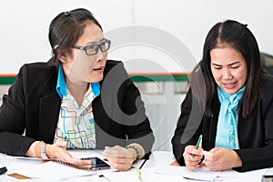 Two asian mid age female colleagues working and doing a presentaion together in office. photo