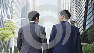 Two asian office worker walking on downtown street in modern city