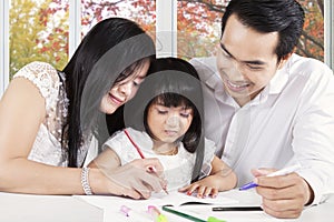 Two asian parents teach their child to write