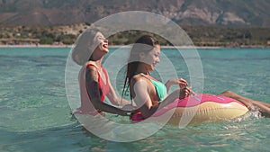 Two asian pretty girls having fun with rubber ring in the sea. Blogger content, travel, friendship, vacation concept