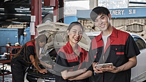 Two Asian professional automotive mechanics working at a service garage.