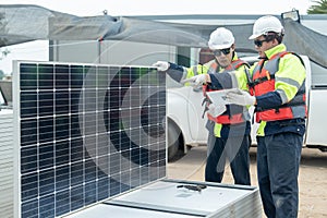 Two Asian professional technician workers hold and discuss using tablet to check solar cell panel and they work in workplace area