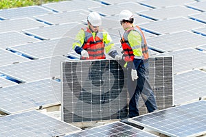 Two Asian professional technician workers with safety uniform stand and help to check or maintenance solar cell panels in area of