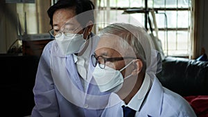 Two Asian senior doctor health care technician looking at patient information and discussing computer screens