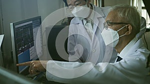 Two Asian senior doctor health care technician looking at patient information and discussing computer screens