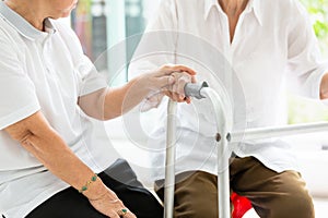 Two asian senior women friends holding hands for care,help and support her friend,time together,old people with walker during