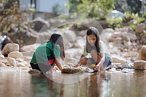 Two asian siblings playing sand nearing the river together with fun.