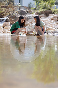 Two asian siblings playing sand nearing the river together with fun.