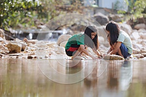 Two asian siblings playing sand nearing the river together with fun.