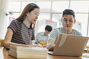 Two asian students researching for project in library