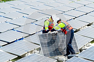 Two Asian technician workers stand and help to install or set up solar panels over water reservoir in the plant for green energy