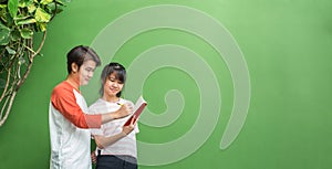 Two of asian teenage students studying together at green wall in