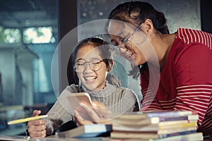 Two asian teenager looking to mobilephone screen with happiness laughing face