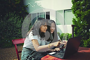 Two asian teenager typing on computer labtop happiness emotion