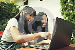 Two asian teenager typing on computer labtop happiness emotion