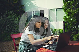 Two asian teenager typing on computer labtop happiness emotion photo