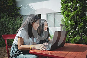 Two asian teenager typing on computer labtop happiness emotion photo