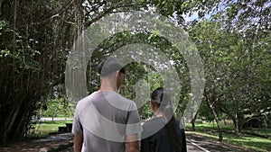 Two asian teenagers walking leisurely together on the street in nature park.