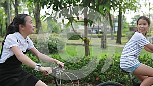 Two asian tennager riding bicycle in public park