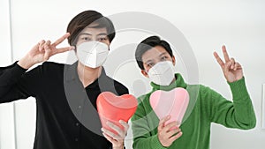 Two Asian woman friends wearing mask with heart balloon support and encourage people form Covid-19 pandemic