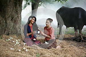 Two Asian woman wearing traditional thai Esan custom style culture sitting in field