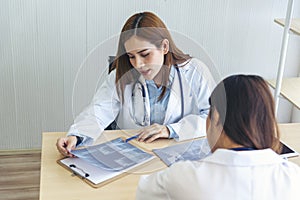 Two asian women doctors discuss meeting doctor`s office medical clinic looking x-ray film consulting patient disease. Asian