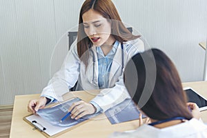 Two asian women doctors discuss meeting doctor`s office medical clinic looking x-ray film consulting patient disease. Asian