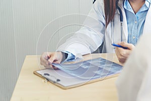 Two asian women doctors discuss meeting doctor`s office medical clinic looking x-ray film consulting patient disease. Asian