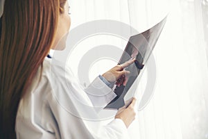 Two asian women doctors discuss meeting doctor`s office medical clinic looking x-ray film consulting patient disease. Asian