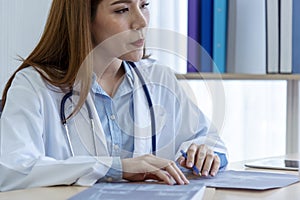 Two asian women doctors discuss meeting doctor`s office medical clinic looking x-ray film consulting patient disease. Asian