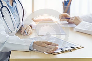 Two asian women doctors discuss meeting doctor`s office medical clinic looking x-ray film consulting patient disease. Asian