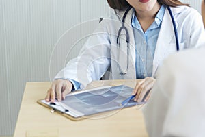 Two asian women doctors discuss meeting doctor`s office medical clinic looking x-ray film consulting patient disease. Asian