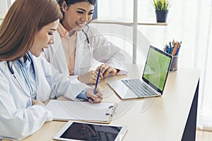 Two asian women doctors discuss meeting doctor`s office medical clinic using laptop consulting patient disease. Asian medical lab