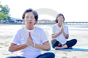Two Asian women doing yoga at the beach.