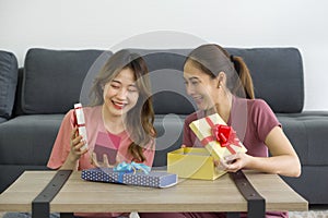 Two Asian women enjoy opening a gift box received for a special occasion