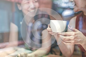 Two Asian women,friends having a free time drinking coffee at cafe. Friends laughing together while drinking a coffee in the