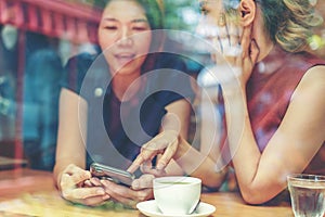 Two Asian women,friends having a free time drinking coffee at cafe. Friends laughing together while drinking a coffee in the