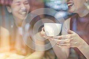 Two Asian women,friends having a free time drinking coffee at cafe. Friends laughing together while drinking a coffee in the resta