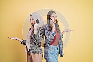 two asian women making phone calls while standing back to back