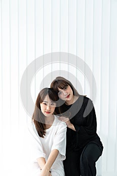 Two asian women sit and laying on each other in pure black and white costume in white backgroud / contrast concept / fashion