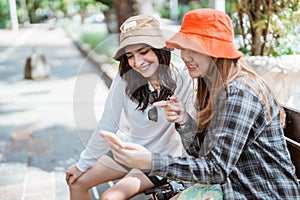 two Asian women use cell phones to search for tourist destinations