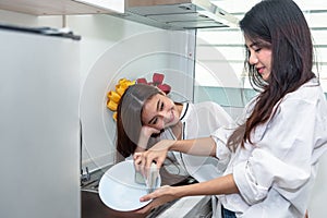 Two Asian women washing dishes together in kitchen. People and Lifestyles concept. LGBT pride and Lesbians theme