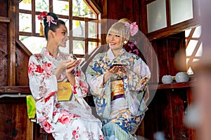 Two Asian women wear japanese style dress sit and enjoy in small shop and also hold small gift and look to each other with