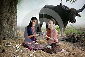 Two Asian woman wearing traditional thai Esan custom style culture sitting in field