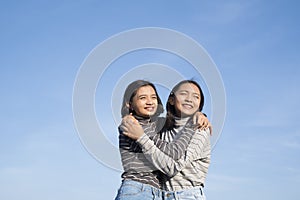 Two Asian young girl standing at the field grass with blue sky