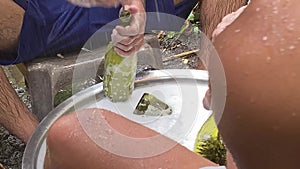 Two Asian young men workers hand washing recycled used wine bottles for local homemade liquor in a humid and showery environment.